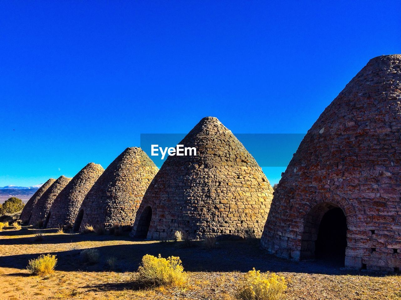 Coke ovens on field against clear blue sky