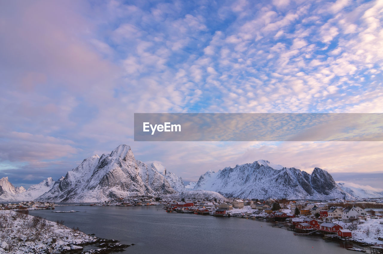 Scenic view of sea by snowcapped mountains against sky during sunset norway