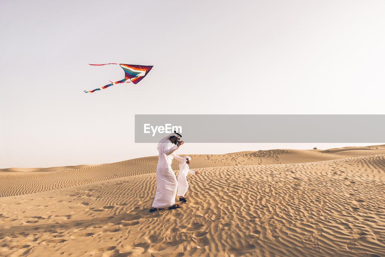 Full length of father with son flying kite in desert