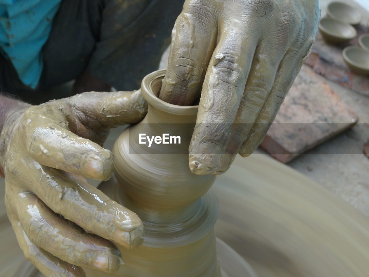 Cropped hands of potter making clay pot at pottery