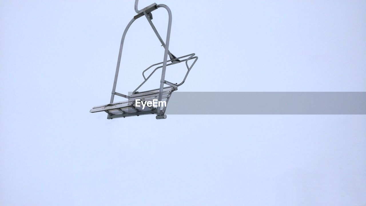 Low angle view of chairlift against foggy sky