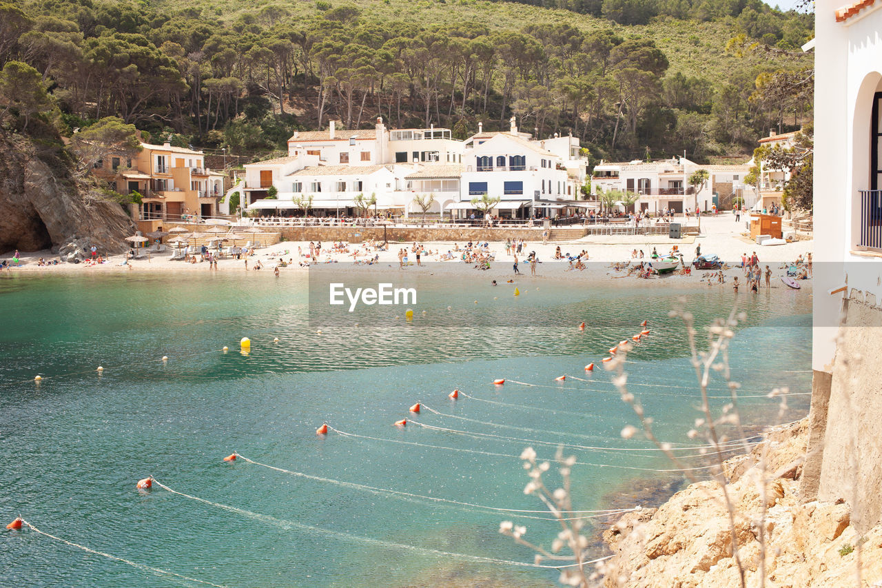 Small beautiful beach with people enjoying sun, sunbathing and swimming in transparent blue sea.