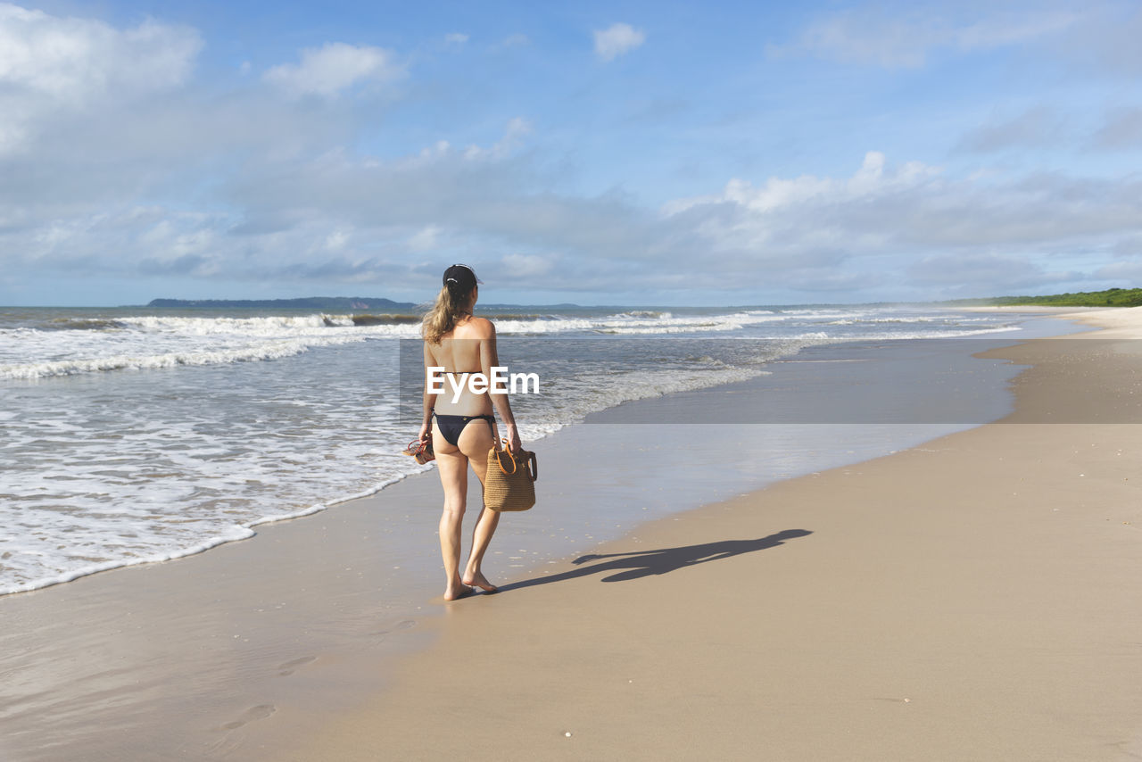 Full length of woman standing at beach against sky
