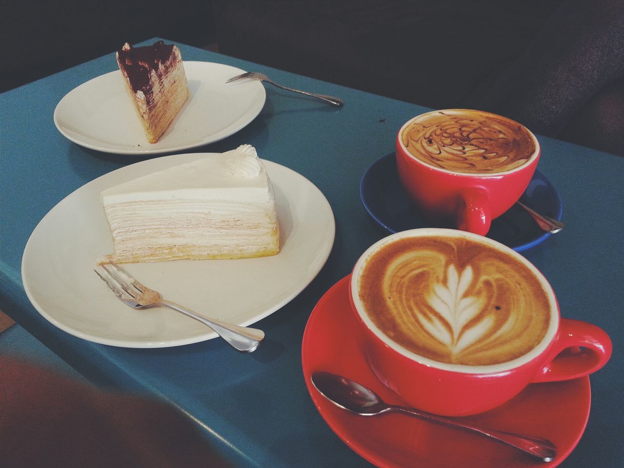 Two cups of cappuccino and two cakes on a tray