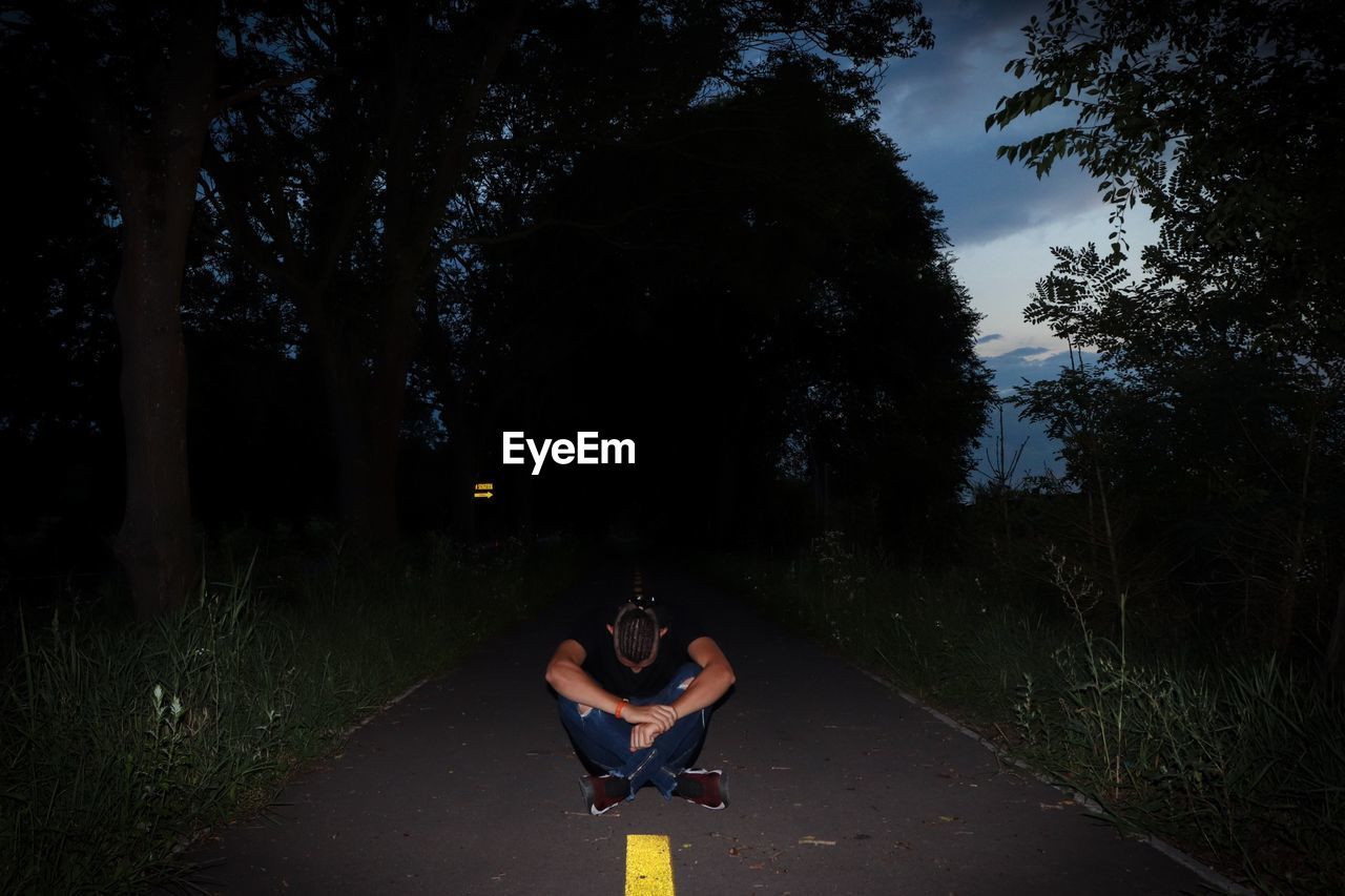Full length of teenager sitting on road at night