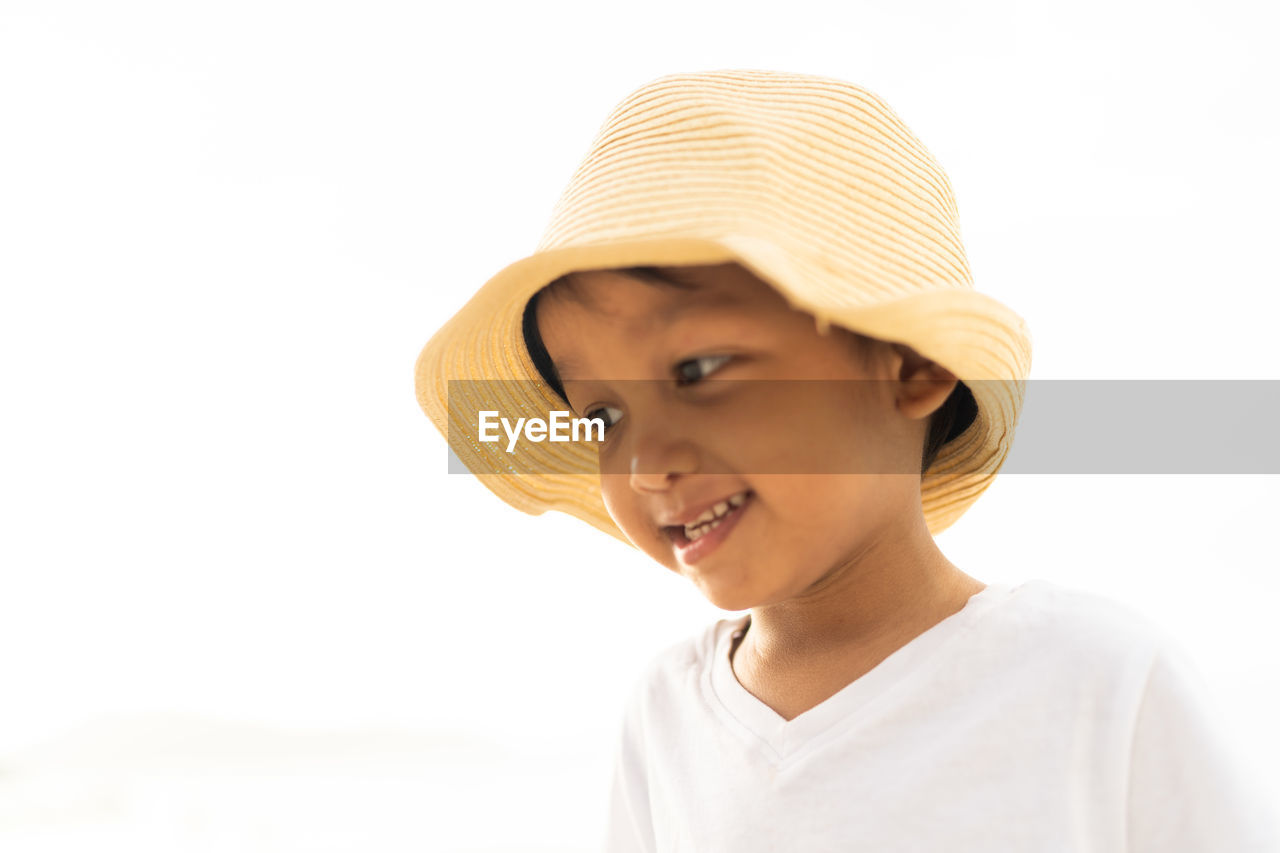 Close-up of boy wearing hat against clear sky in summer