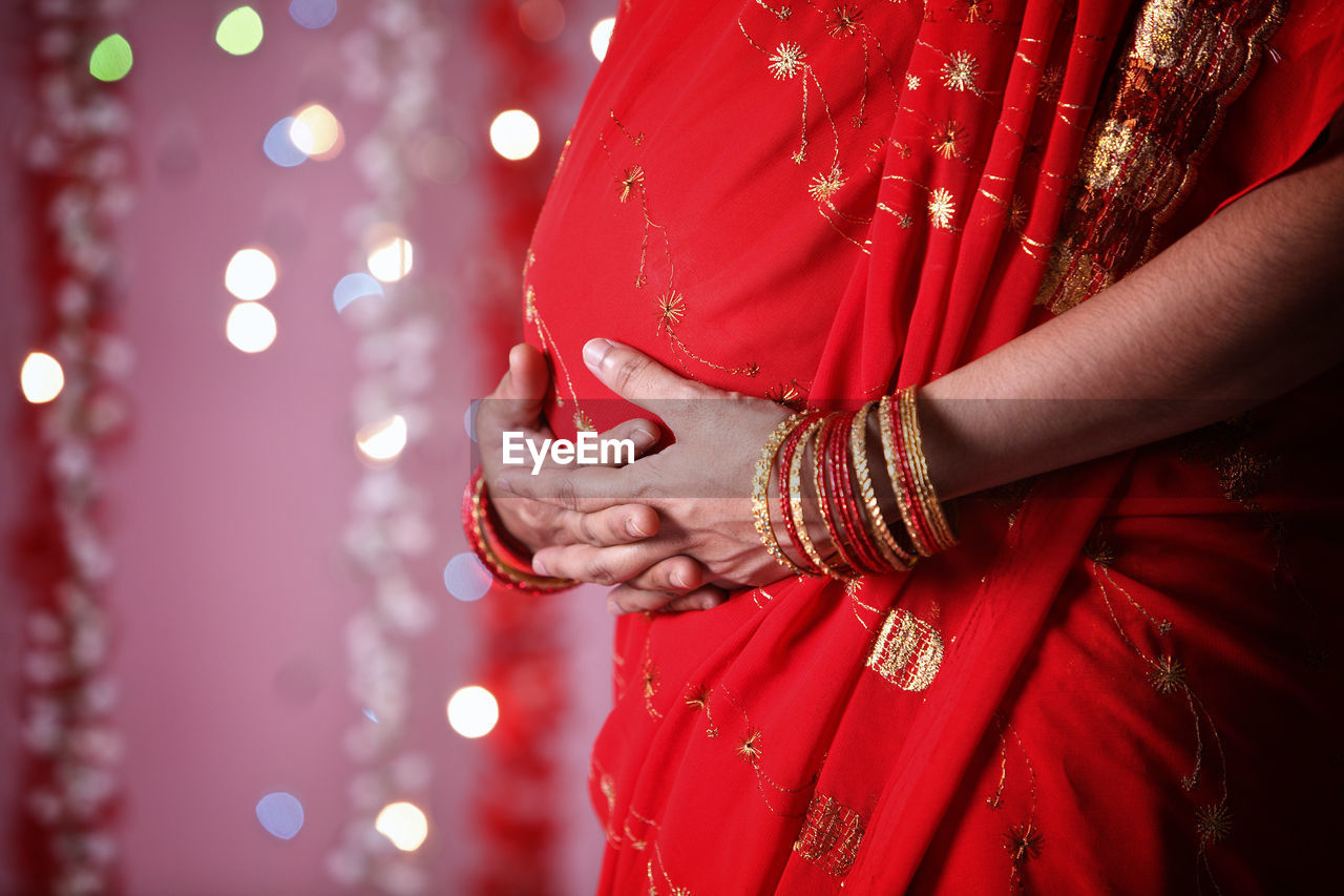 Midsection of pregnant woman in red sari during diwali