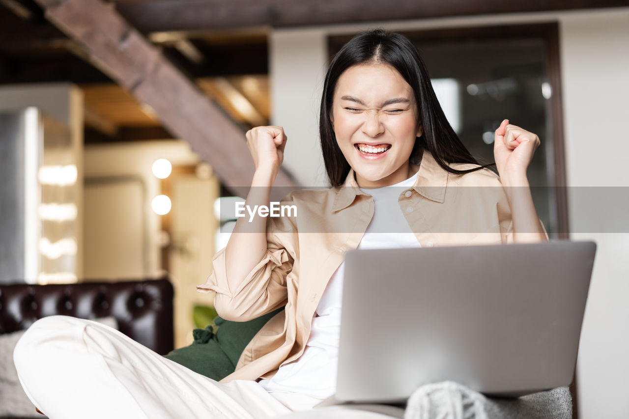 portrait of smiling woman using laptop while sitting on table