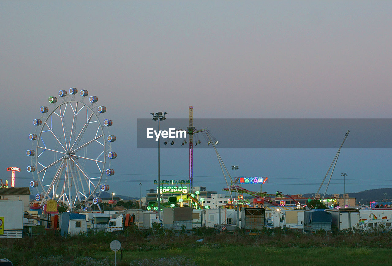 Ferries wheel by built structures against the sky