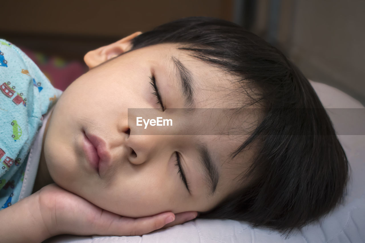 Close-up of young boy sleeping on bed