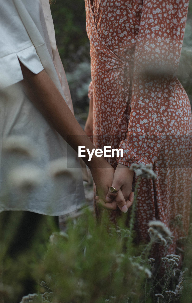 Midsection of woman holding hands while standing at park