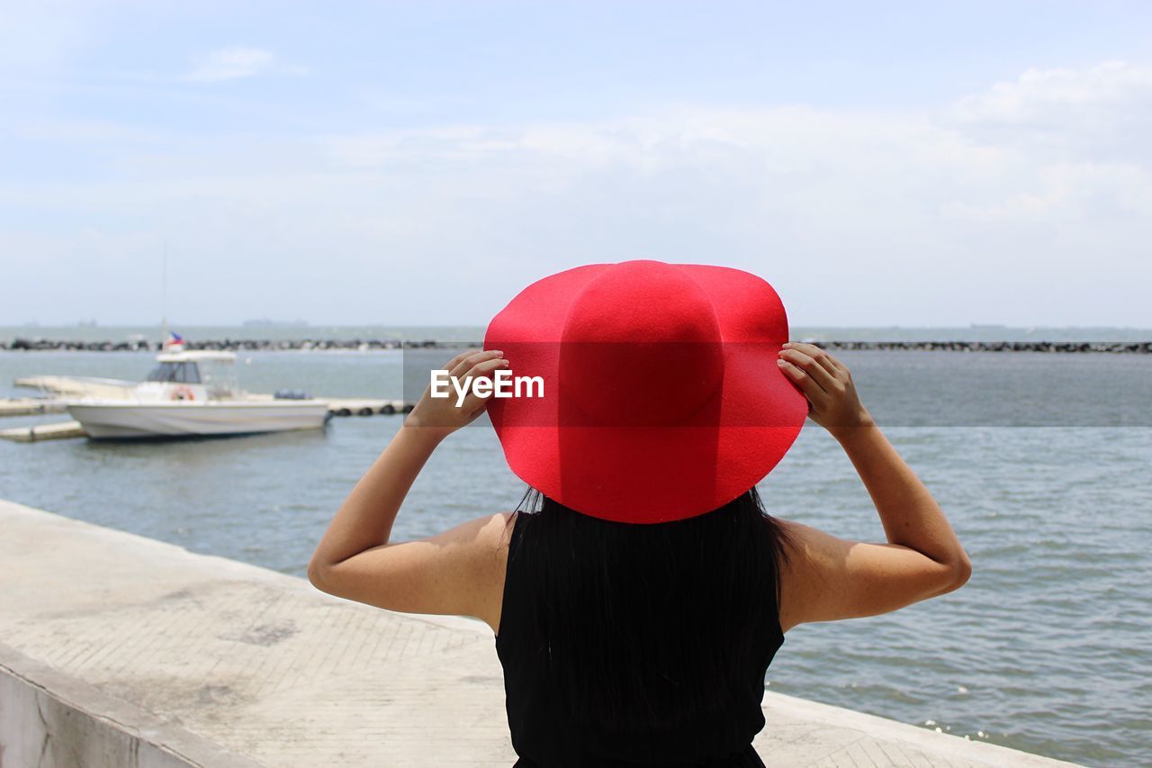 Rear view of woman wearing red hat against sea