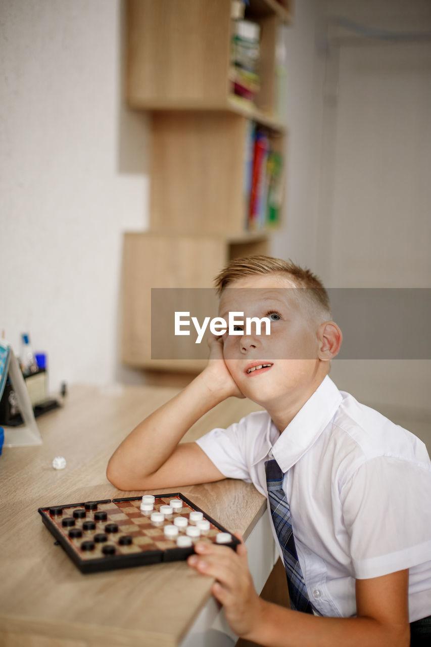 Boy looking up playing board game at home