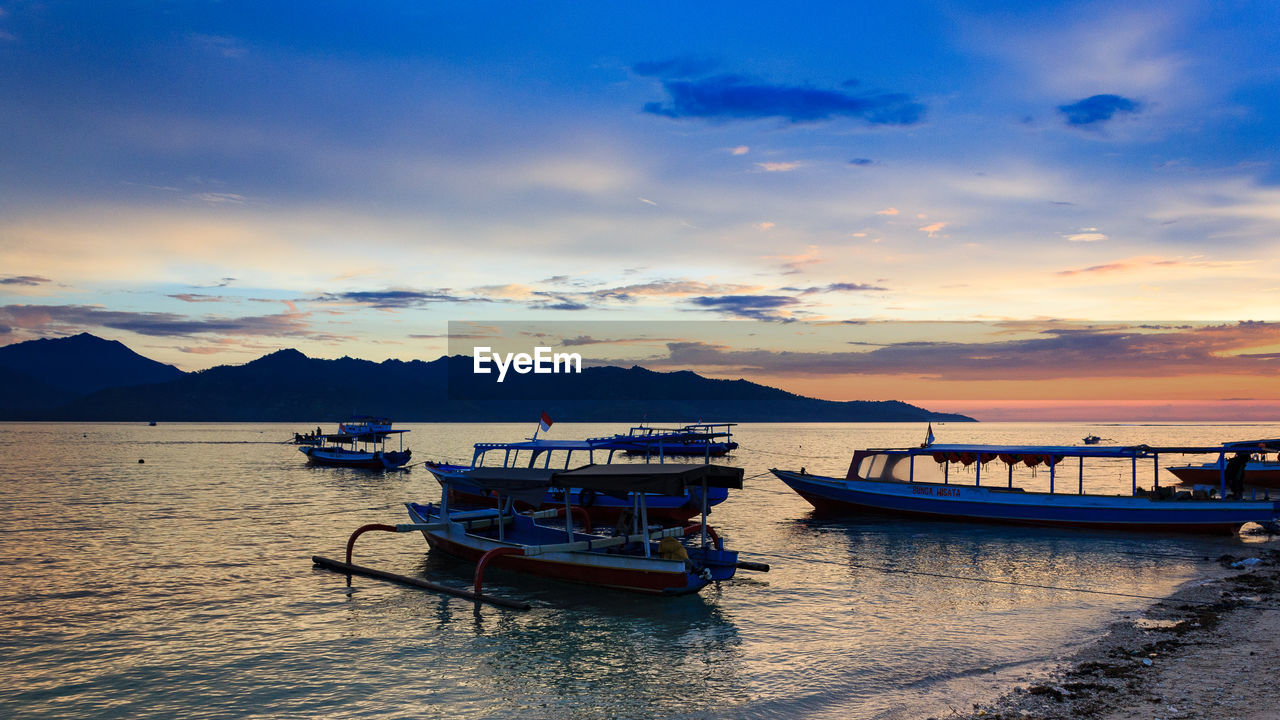 BOATS MOORED ON SEA AGAINST SKY DURING SUNSET