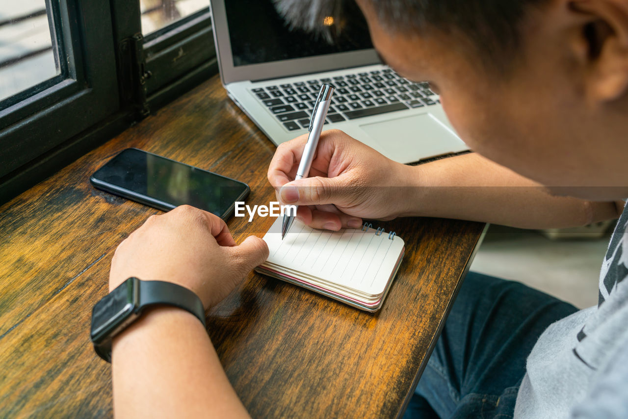 Man writing in notepad at table