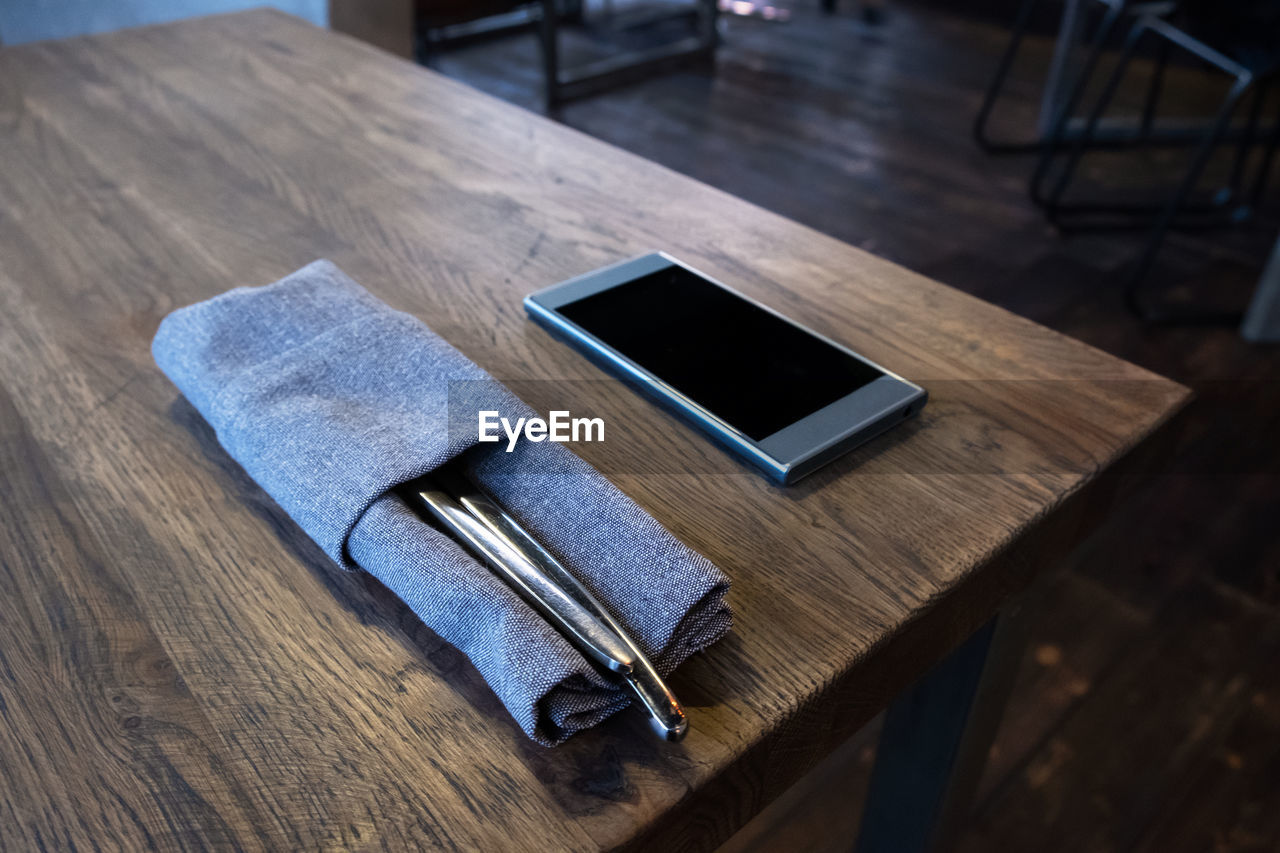 High angle view of napkin and smart phone on wooden table