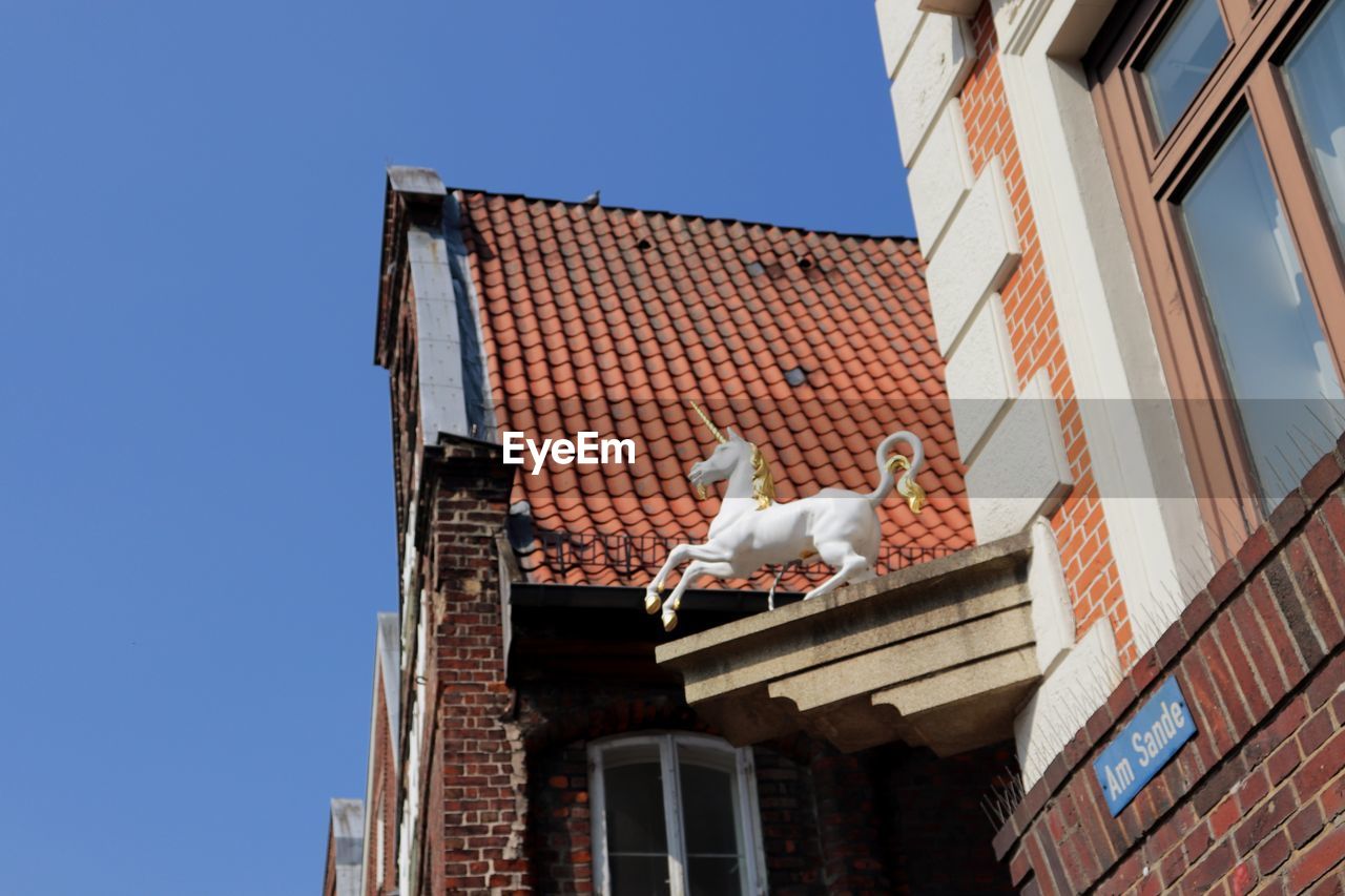 LOW ANGLE VIEW OF BIRD ON BUILDING AGAINST SKY