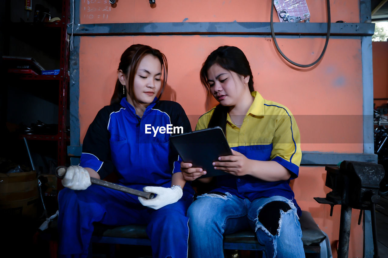 Portrait of young woman using digital tablet while sitting in cafe