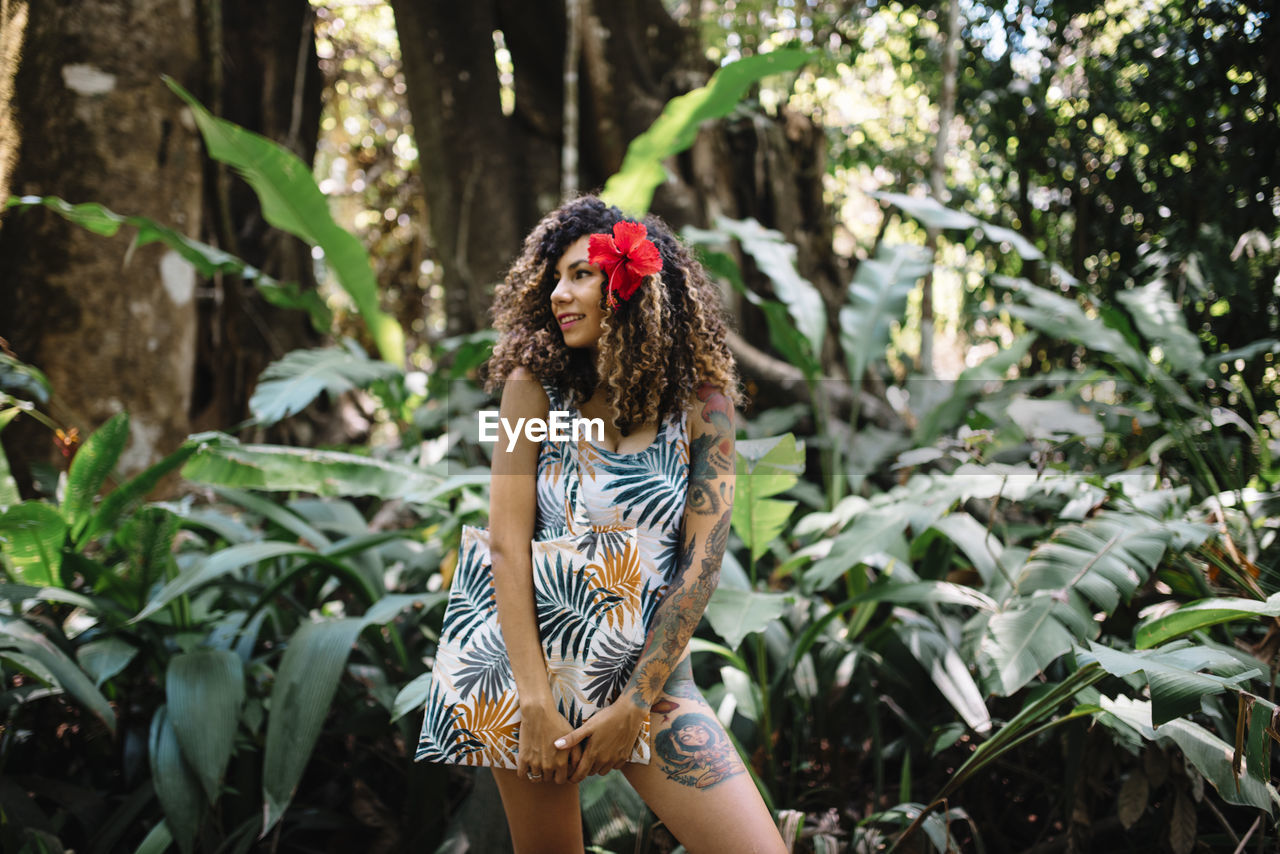 Young woman standing against plants in forest