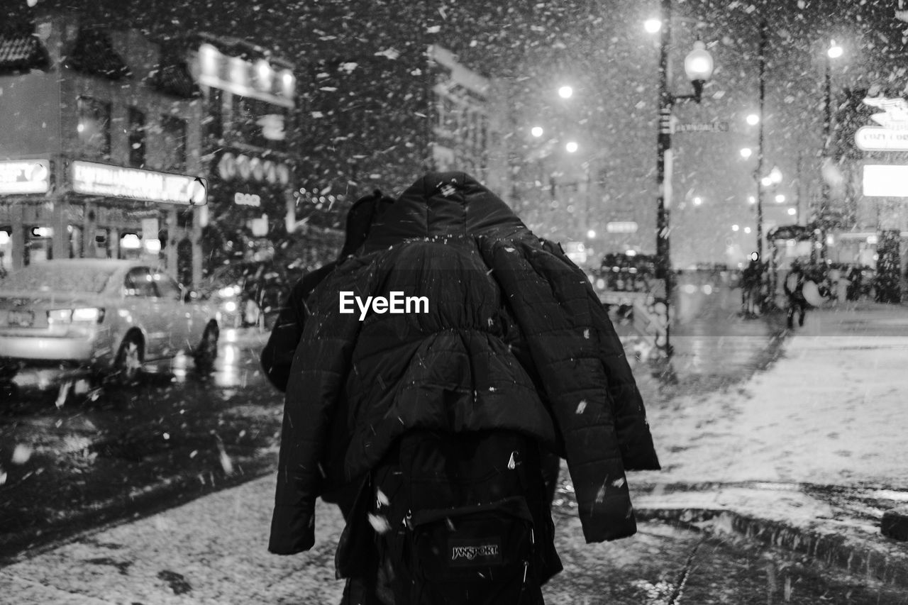 REAR VIEW OF MAN ON WET STREET IN RAINY SEASON