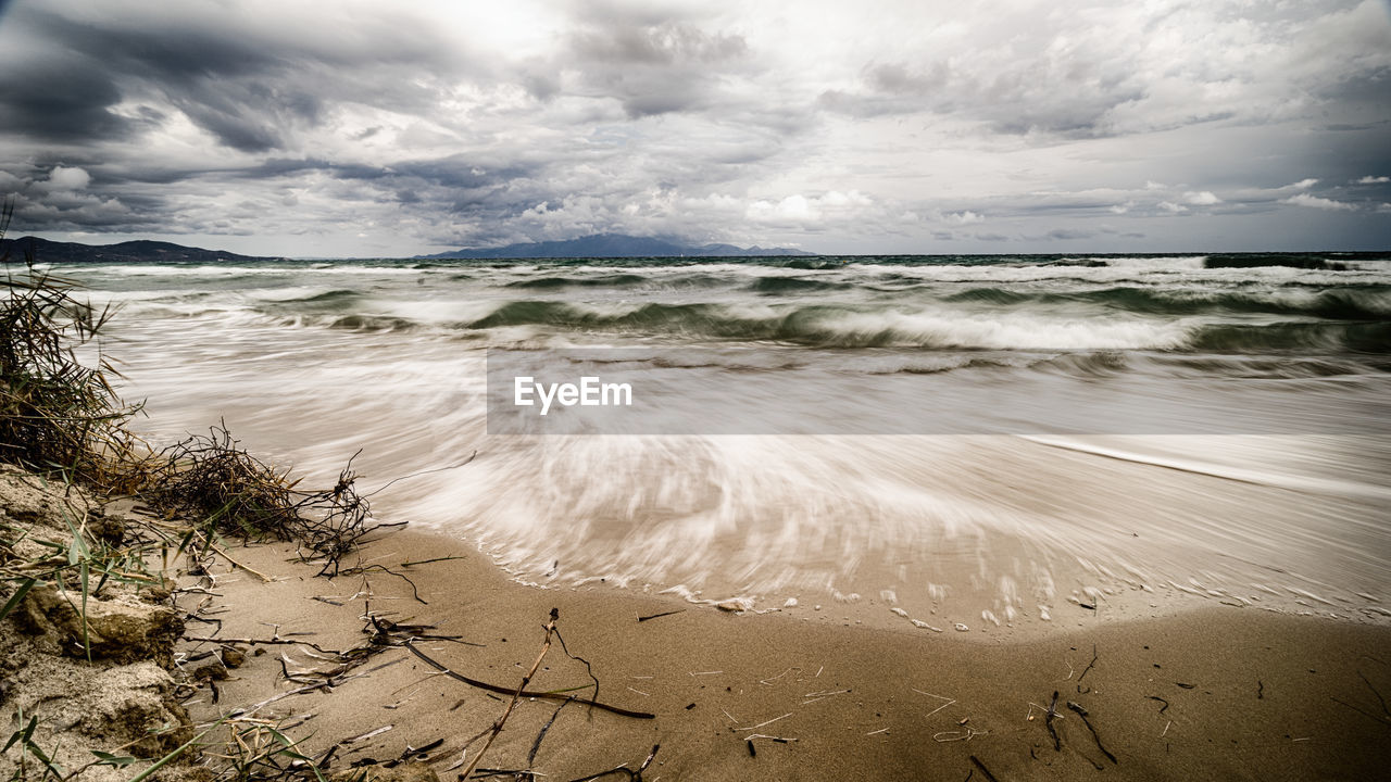 Scenic view of beach against cloudy sky