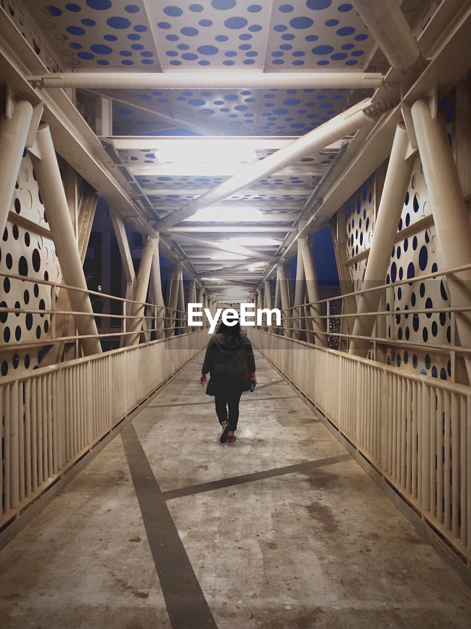 REAR VIEW OF MEN WALKING ON ELEVATED WALKWAY