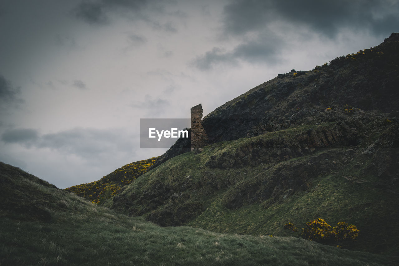 Low angle view of castle on mountain against cloudy sky