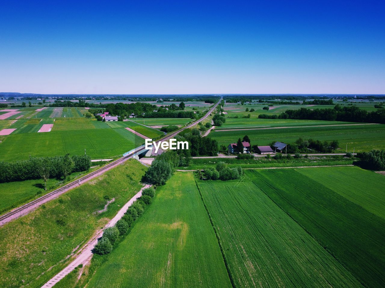 landscape, field, environment, plain, grass, agriculture, plant, land, rural scene, sky, nature, green, aerial photography, farm, scenics - nature, rural area, hill, horizon, grassland, day, growth, beauty in nature, outdoors, blue, crop, sport venue, clear sky, transportation, high angle view, sports, tranquil scene, travel, tranquility, tree, race track, sunny, sunlight, no people