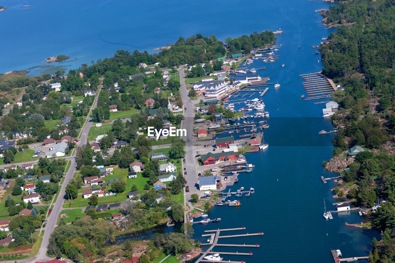 HIGH ANGLE VIEW OF BUILDINGS AND TREES BY SEA