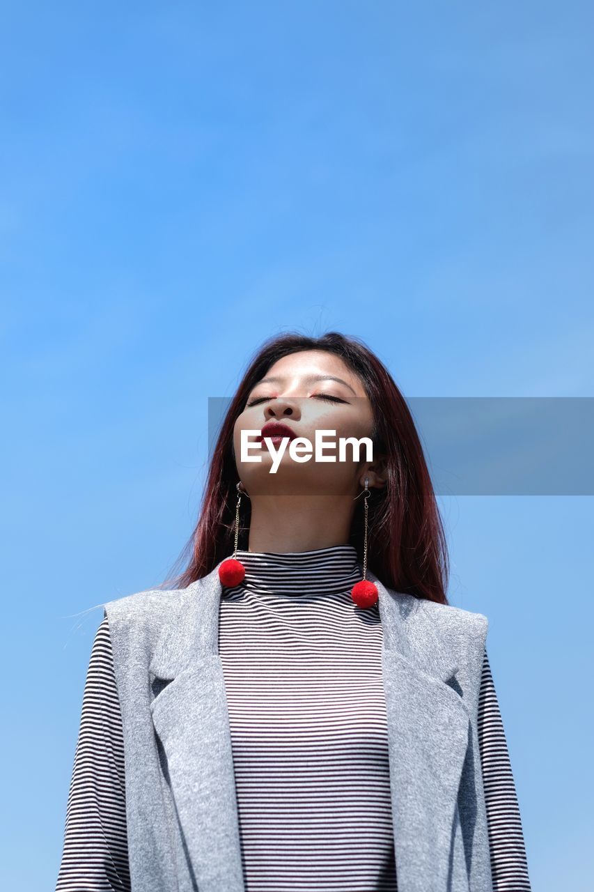 Low angle view of woman against blue sky