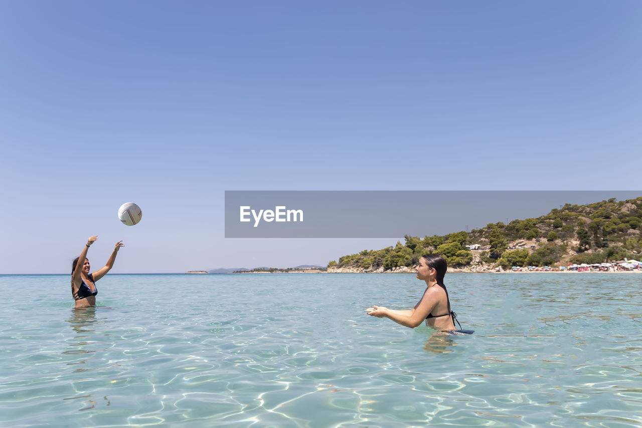 Happy teenagers playing volleyball in water at the vacation and fun