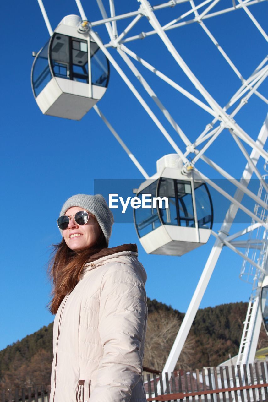 Low angle view of young woman standing against sky