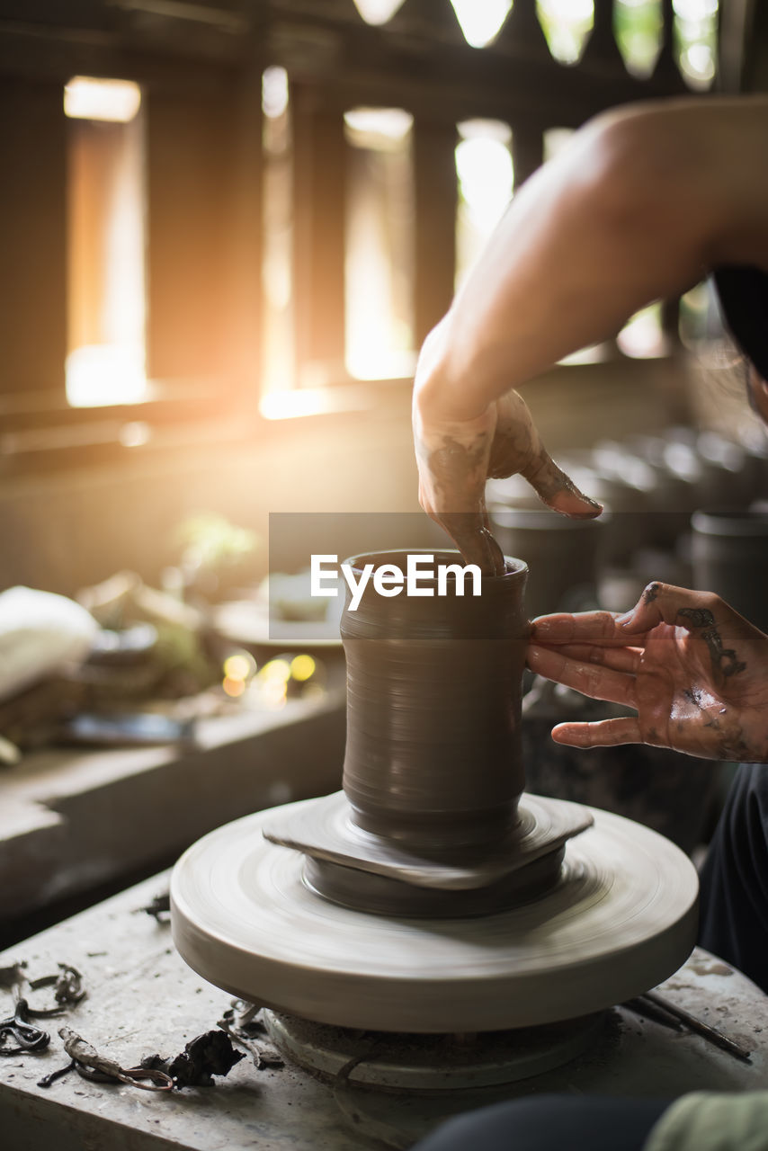 Midsection of woman making pottery in workshop