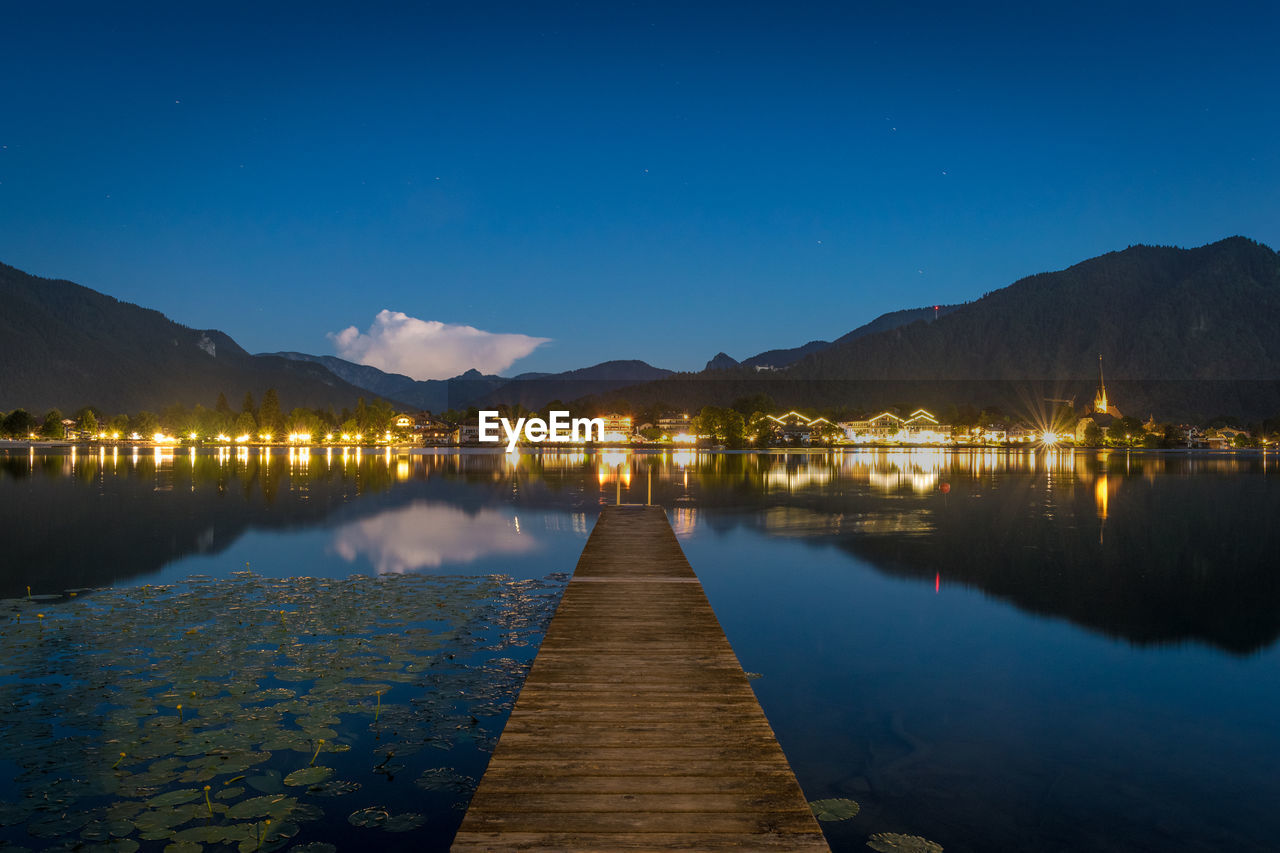 Pier over lake against sky at night