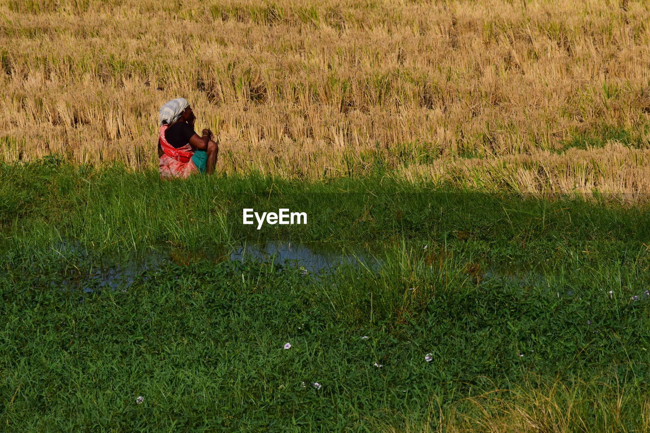 REAR VIEW OF WOMAN ON FIELD BY LAND