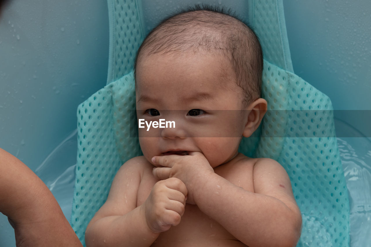 Cute baby girl lying in container