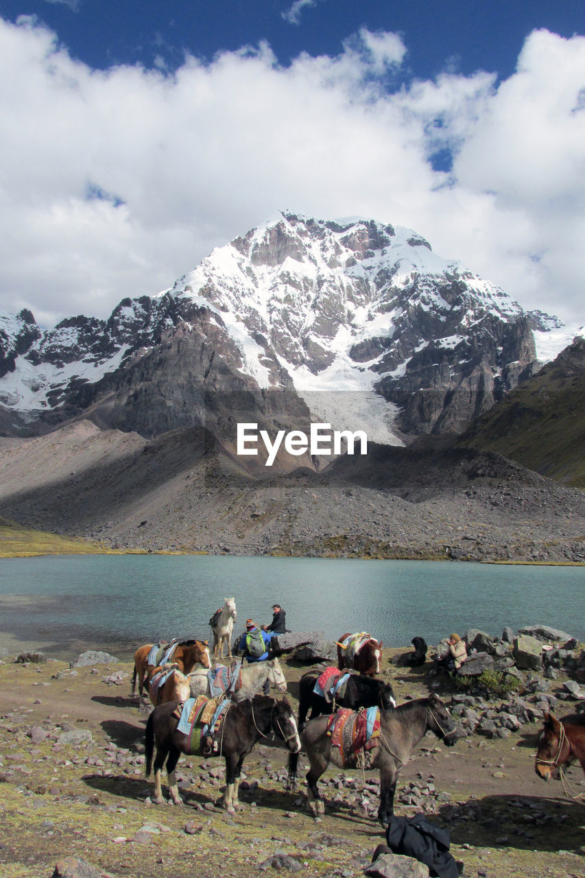 MEN WITH SNOWCAPPED MOUNTAIN AGAINST SKY