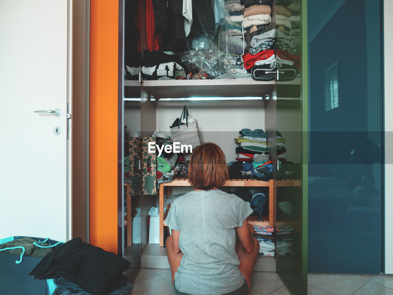 Rear view of woman looking in cabinet while sitting at home