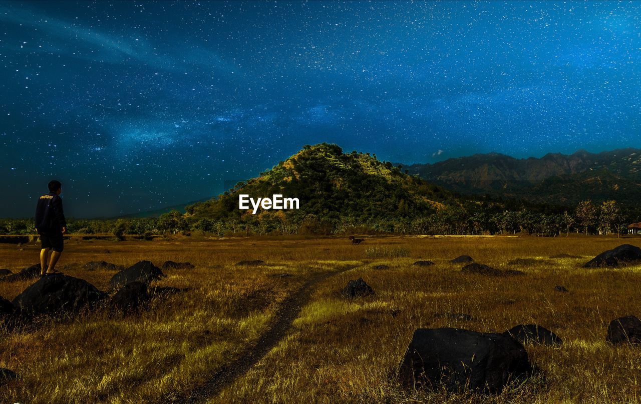 Man standing on field against sky at night