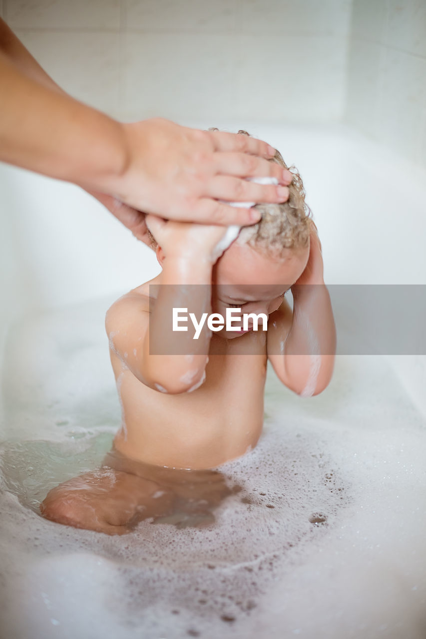 Cropped hands of parent bathing baby boy