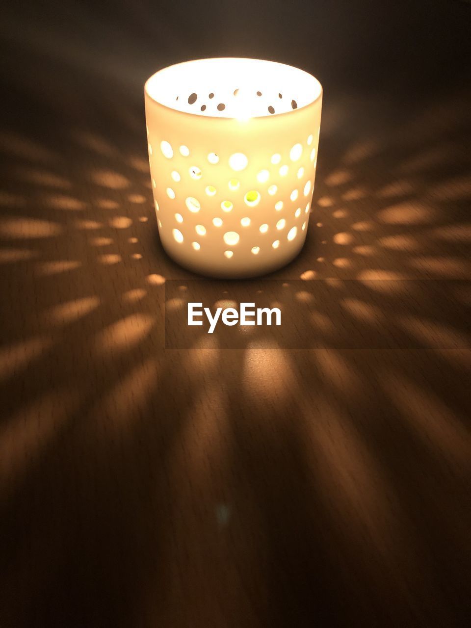 CLOSE-UP OF ILLUMINATED CANDLE ON TABLE