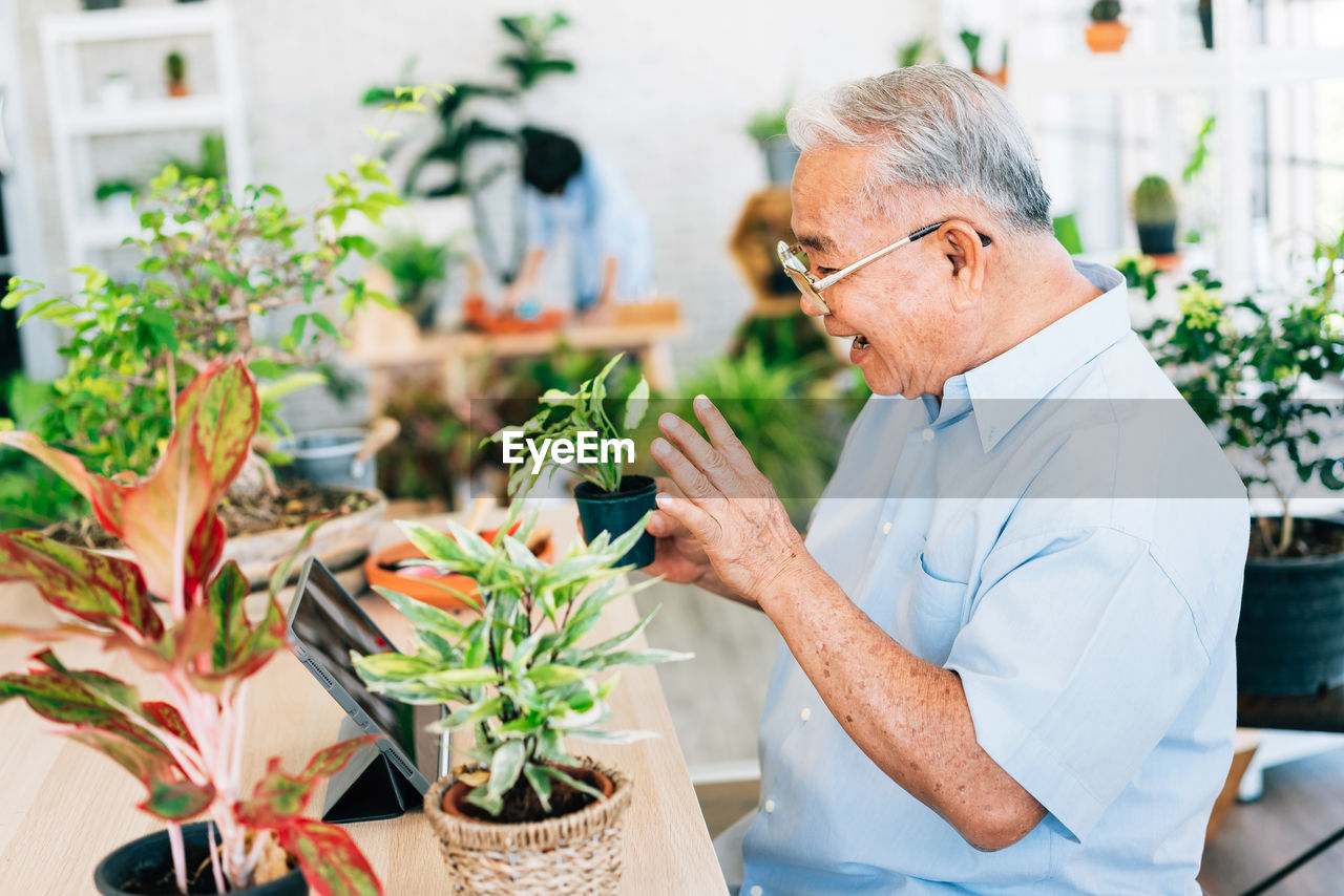 Cheerful man holding plant at botany