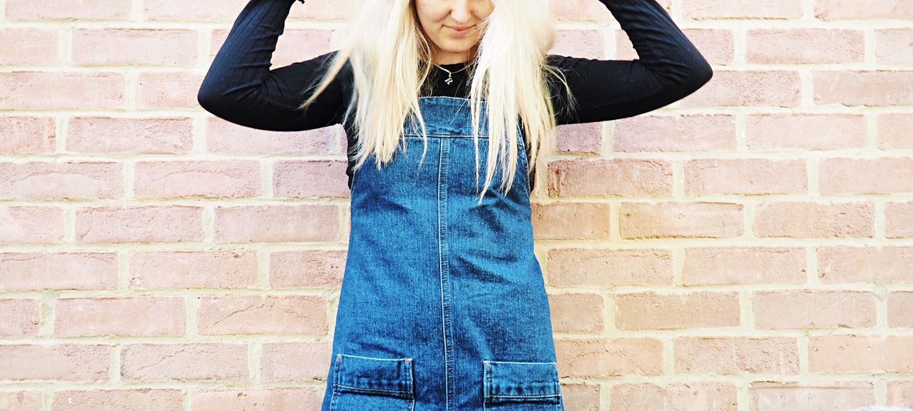 Midsection of woman standing against brick wall