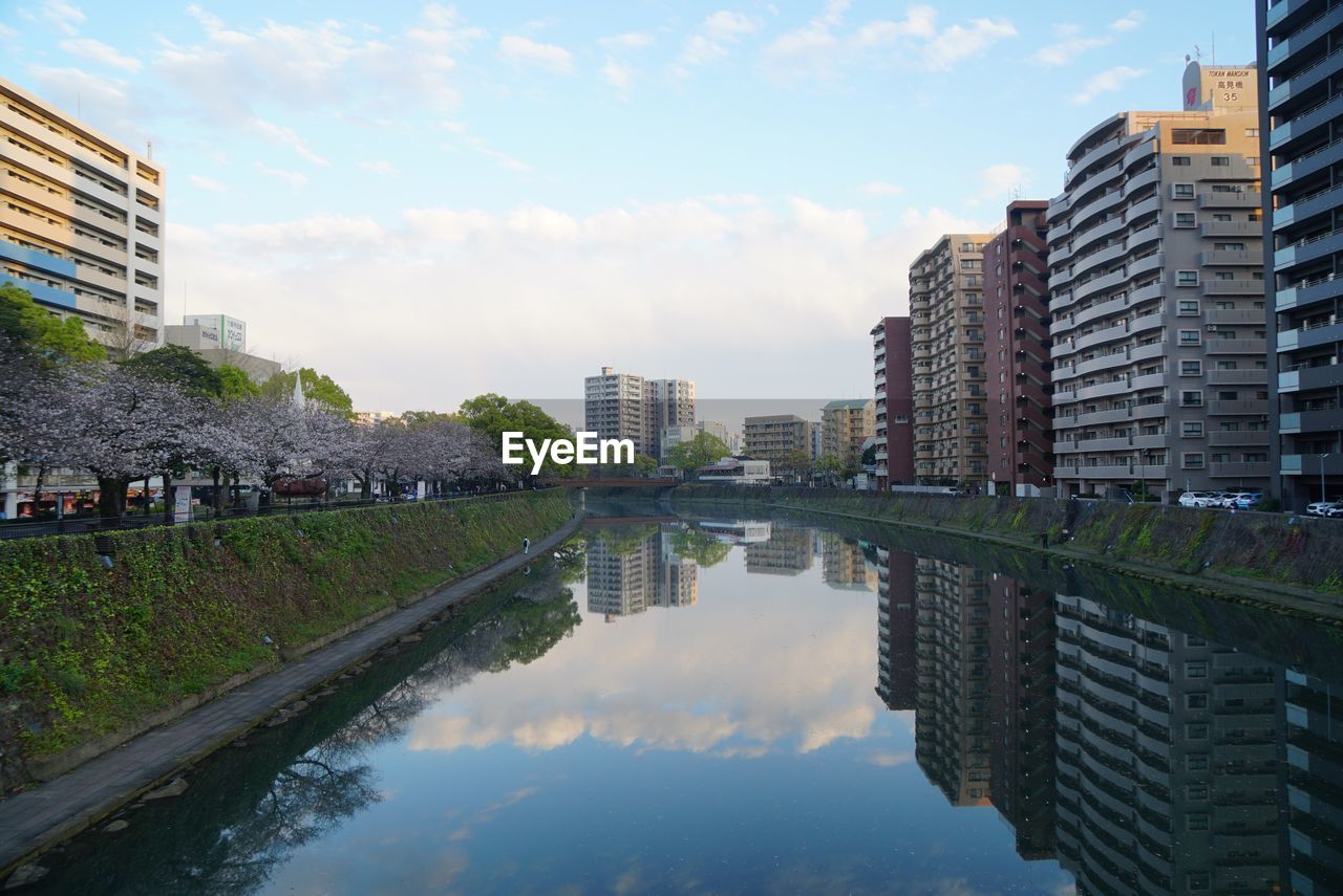 Reflection of buildings in river against sky