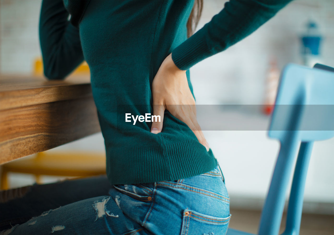 Midsection of woman with backache sitting on chair