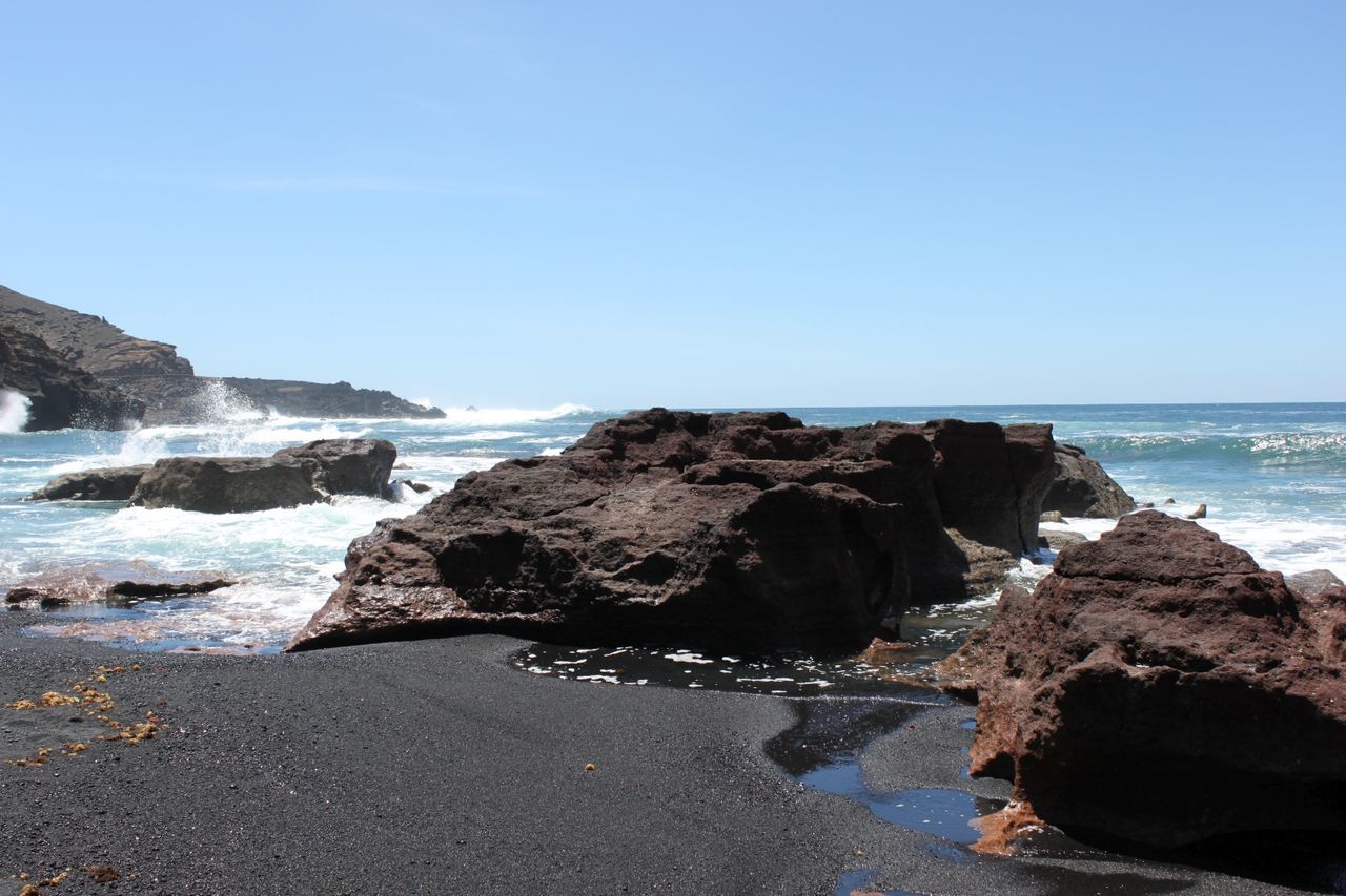 Rocks on beach against clear sky