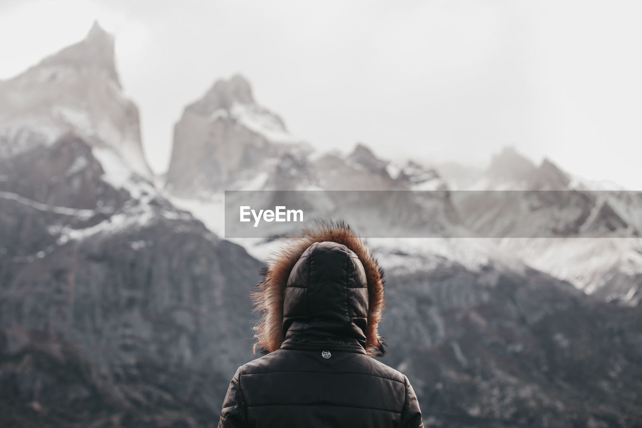 Rear view of person standing against snowcapped mountain