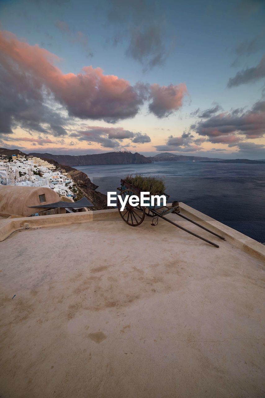 Push cart on building terrace by sea against sky