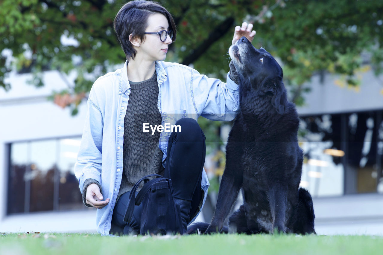 MAN WITH DOG LOOKING AWAY WHILE SITTING ON PERSON