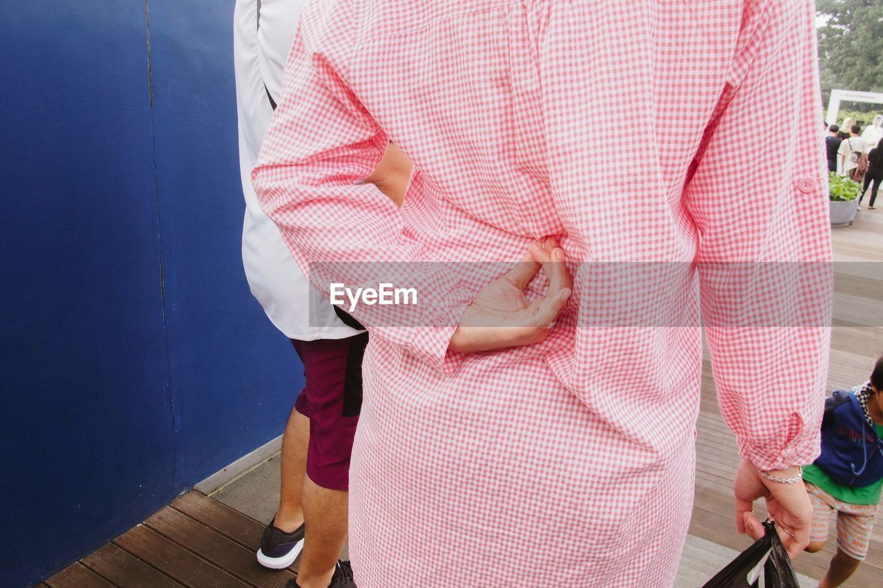 Midsection of woman wearing pink dress standing on footpath